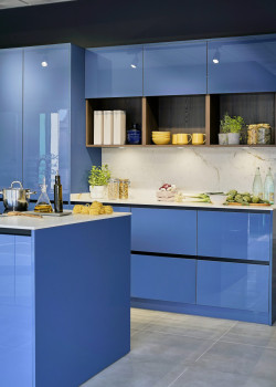 Virtuve ar glancētām spilgti zilām fasādēm, baltu virsmu