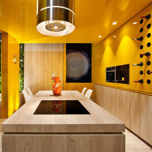 Telpa ar gaišu koka galdu un akcentu gar sienu un karija dzeltenu krāsu sienām